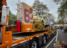 Verschoor Kraanverhuur uit Sassenheim. In 1971 reed Maarten senior voor het eerst mee met het Bloemencorso in zijn nieuwste kraan. Nu ruim 50 jaar later rijden ze mee met hun eigen wagen en vieren ze hun 60-jarig jubileum.